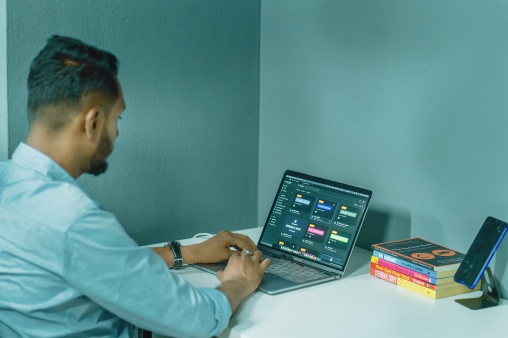 a-man-sitting-at-a-desk-using-a-laptop-computer-p5aywcbmfji