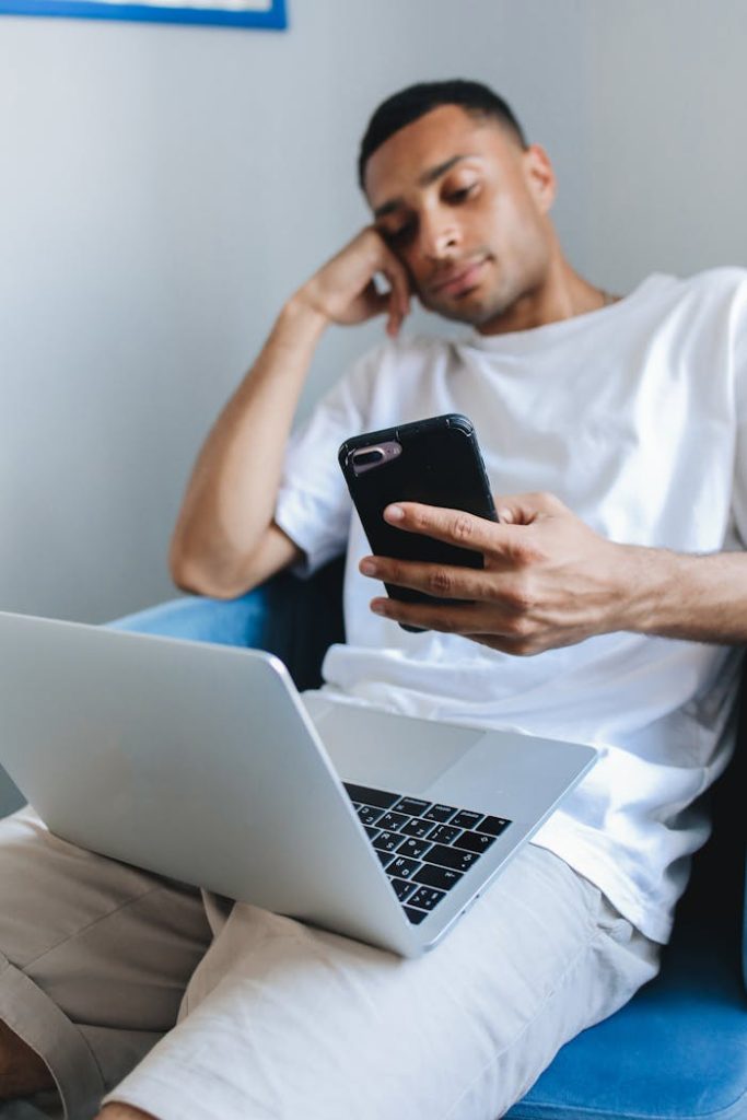 Man in casual wear studying with laptop and smartphone indoors.